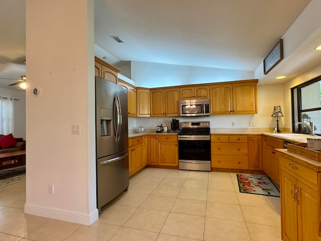 kitchen featuring sink, vaulted ceiling, ceiling fan, light tile patterned floors, and appliances with stainless steel finishes