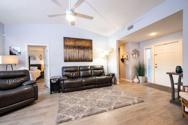 living room with a textured ceiling, light hardwood / wood-style flooring, ceiling fan, and vaulted ceiling