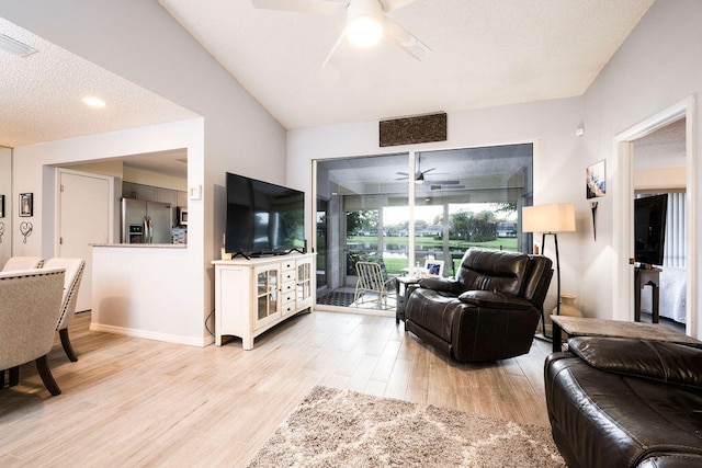 living room featuring a textured ceiling, light hardwood / wood-style flooring, ceiling fan, and vaulted ceiling