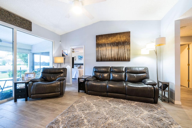 living room featuring ceiling fan, light wood-type flooring, and vaulted ceiling