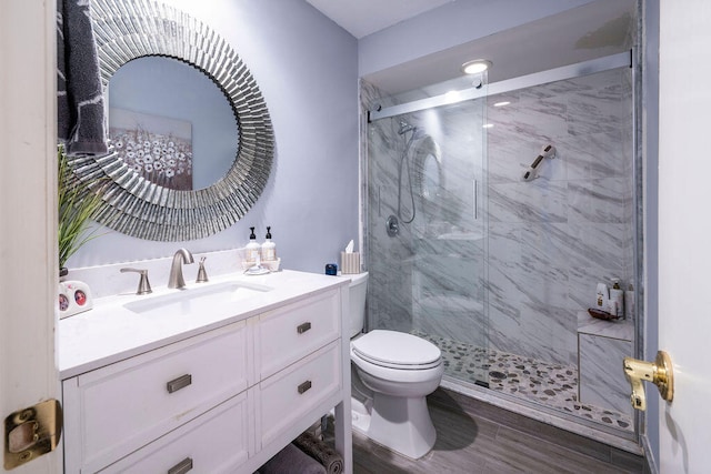 bathroom with hardwood / wood-style floors, vanity, toilet, and a shower with door