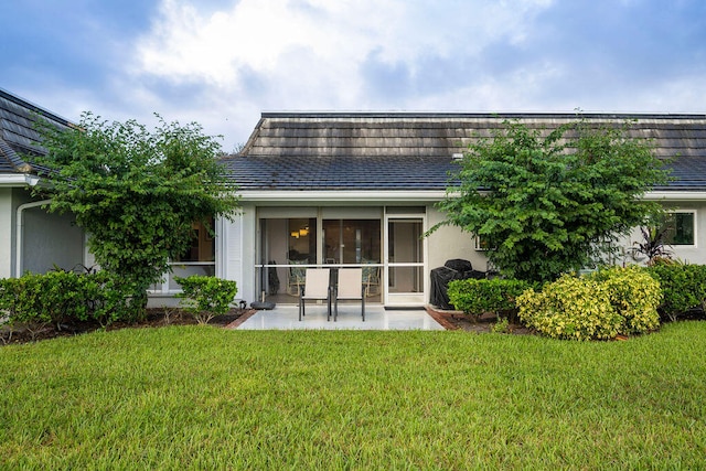 rear view of property with a lawn and a patio area