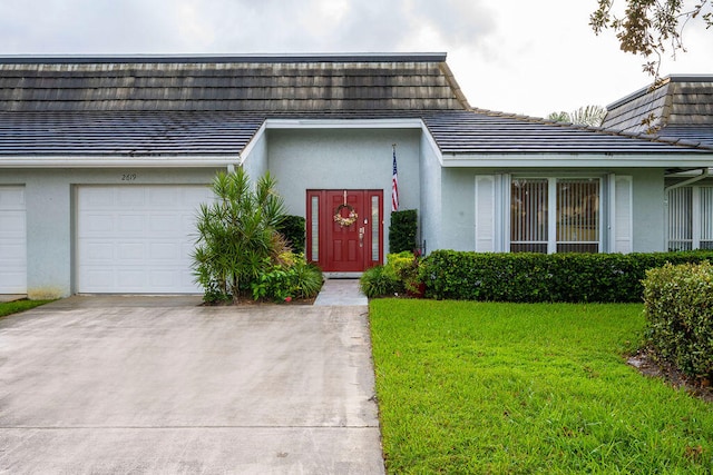 doorway to property featuring a garage and a lawn