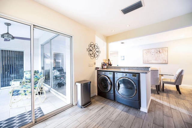 clothes washing area featuring independent washer and dryer and light hardwood / wood-style flooring