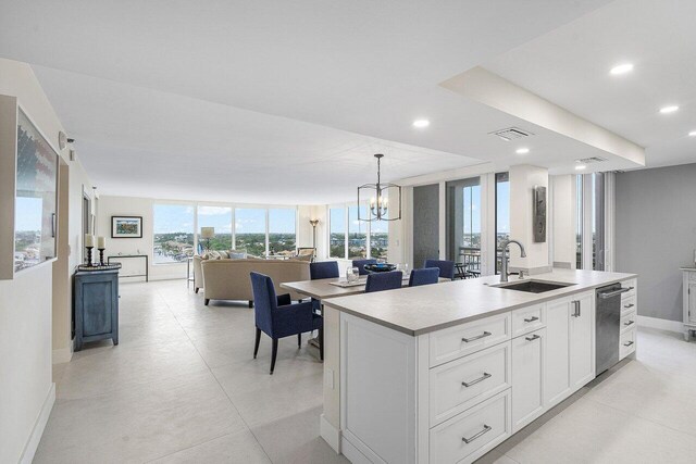 kitchen featuring pendant lighting, sink, white cabinets, dishwasher, and a kitchen island with sink