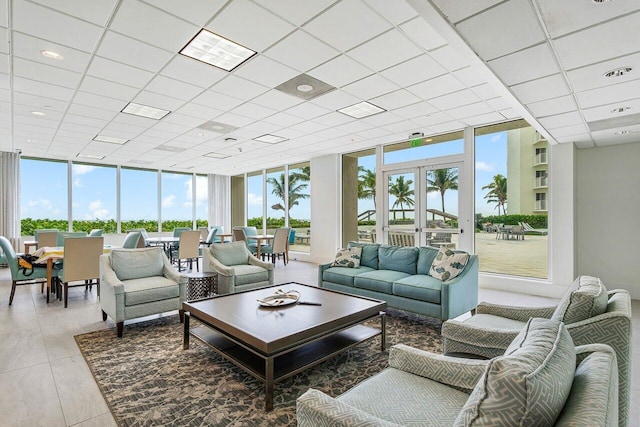 living room featuring expansive windows, wood-type flooring, and a drop ceiling