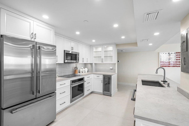 kitchen featuring white cabinets, stainless steel appliances, sink, and beverage cooler