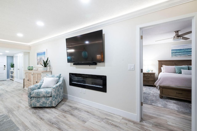 living area featuring light wood-type flooring, ceiling fan, and ornamental molding