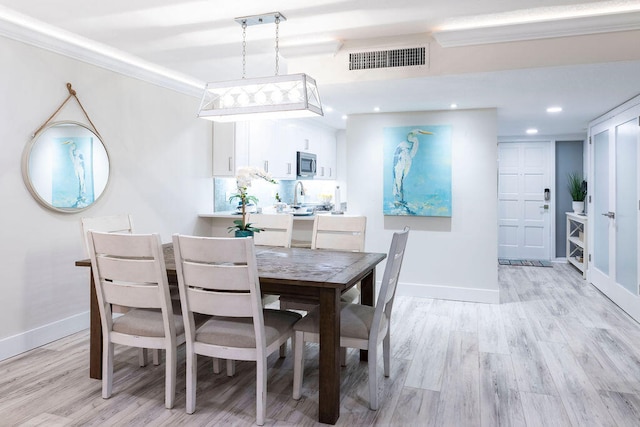 dining space featuring light wood-type flooring and ornamental molding