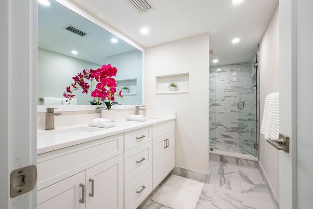 bathroom featuring a shower with door and vanity