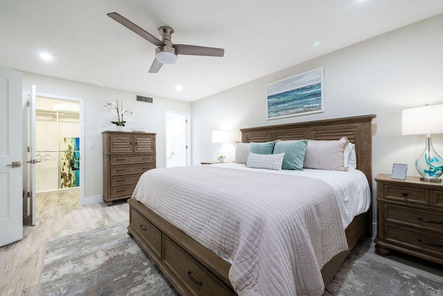 bedroom with ceiling fan, a closet, light wood-type flooring, and a spacious closet