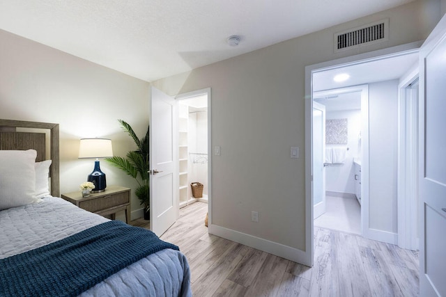 bedroom with light wood-type flooring and ensuite bathroom