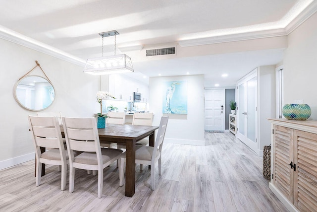 dining area with light hardwood / wood-style flooring and ornamental molding