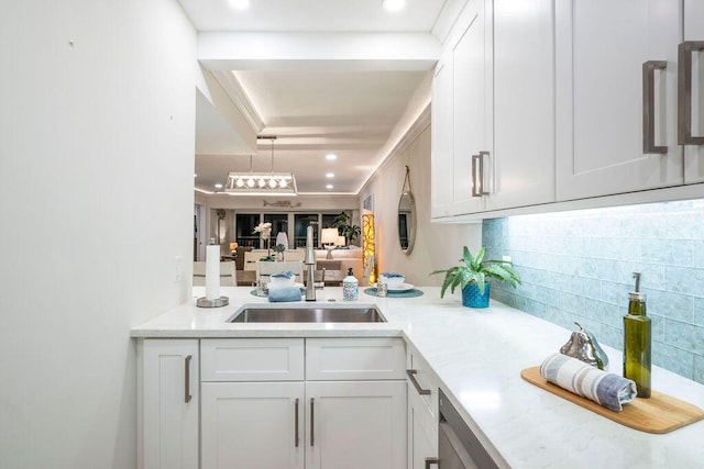 interior space with white cabinets, sink, and backsplash