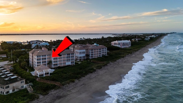 aerial view at dusk with a water view and a view of the beach