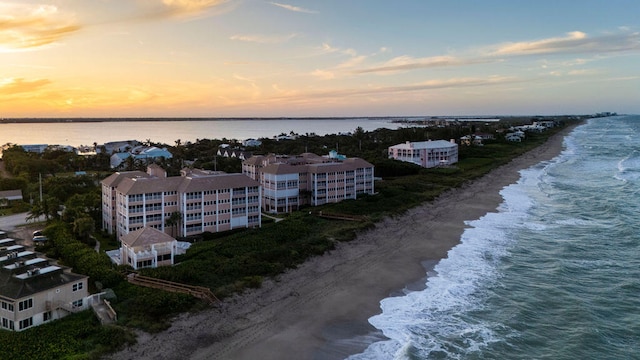 aerial view at dusk with a view of the beach and a water view