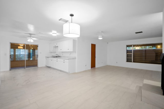 unfurnished living room featuring sink, plenty of natural light, and ceiling fan