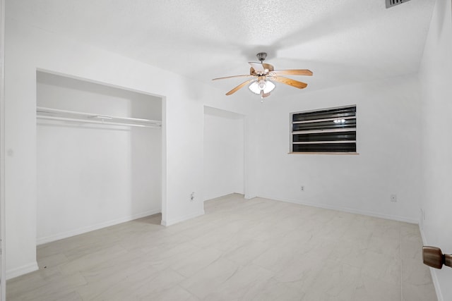 unfurnished bedroom with ceiling fan and a textured ceiling