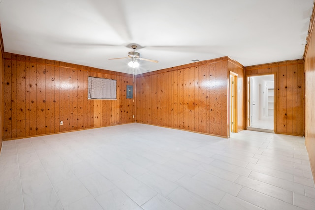 empty room with electric panel, ceiling fan, and wood walls