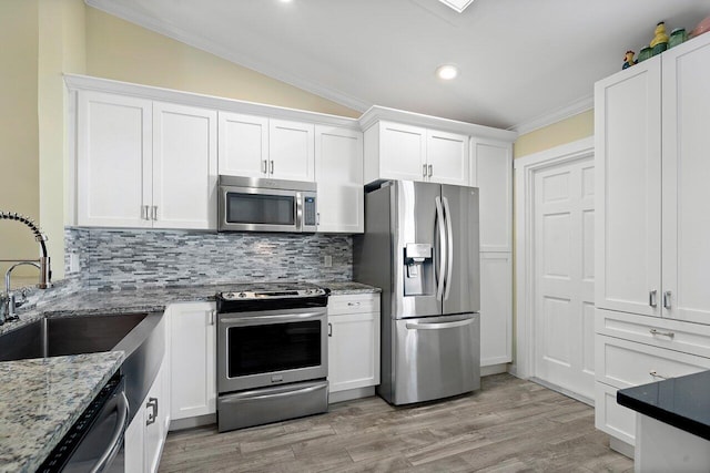 kitchen featuring white cabinets, stainless steel appliances, light stone countertops, and lofted ceiling