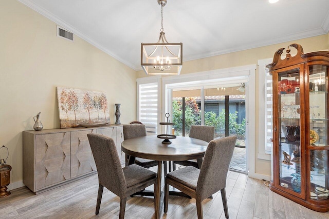 dining area with a notable chandelier, light hardwood / wood-style floors, and crown molding