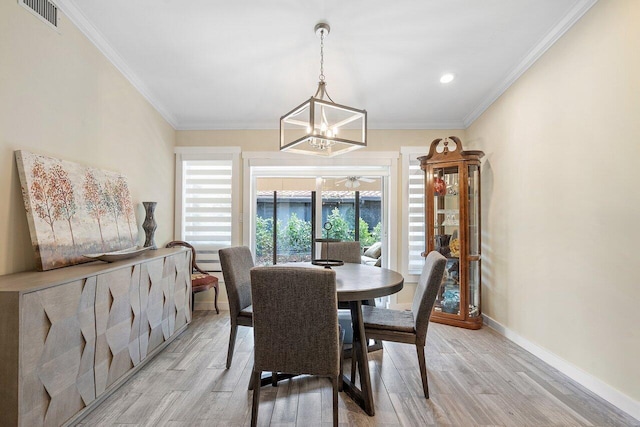 dining area with crown molding, light hardwood / wood-style floors, and a notable chandelier