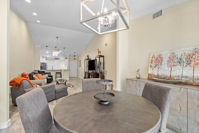 dining room featuring ceiling fan with notable chandelier, light hardwood / wood-style floors, lofted ceiling, and ornamental molding