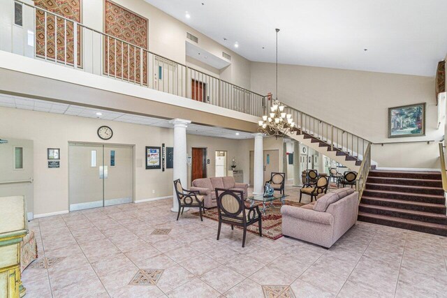 tiled living room with an inviting chandelier, high vaulted ceiling, and ornate columns