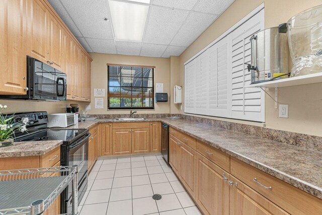 kitchen featuring black appliances, a drop ceiling, light tile patterned floors, and sink