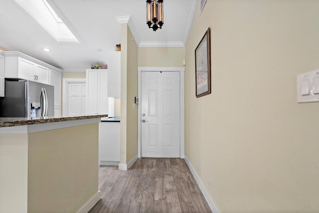 interior space with a skylight, crown molding, and light hardwood / wood-style flooring