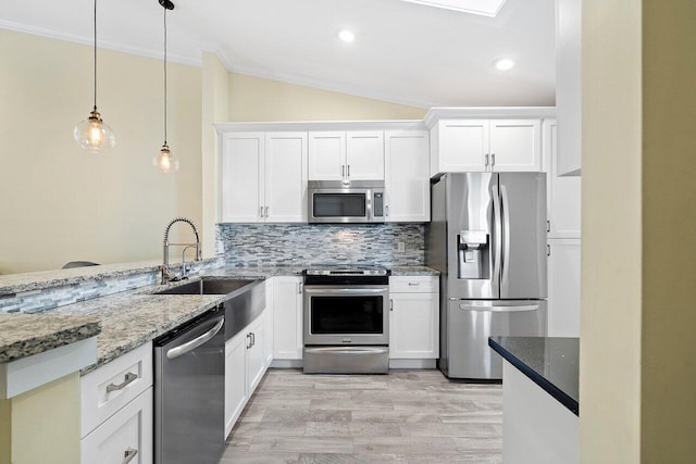 kitchen with appliances with stainless steel finishes, white cabinetry, lofted ceiling, and sink