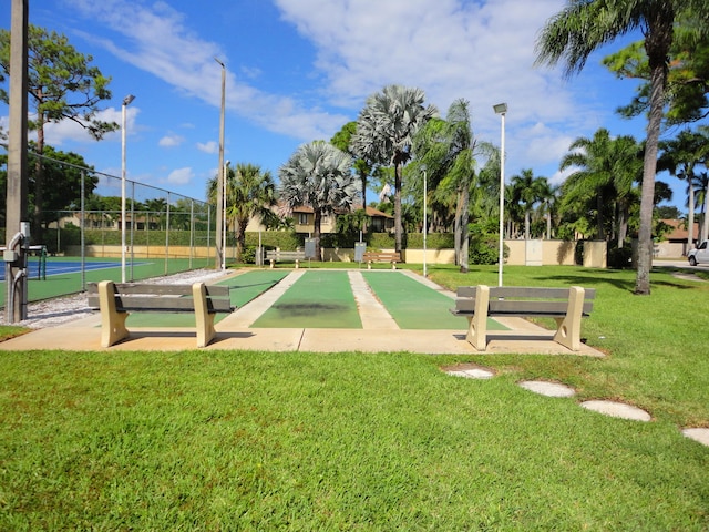 view of home's community featuring tennis court and a lawn