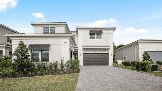 view of front of home featuring a front yard, central AC, and a garage