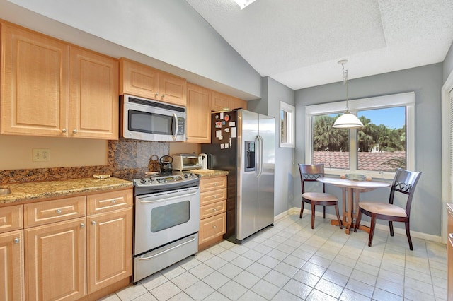 kitchen with light stone counters, appliances with stainless steel finishes, a textured ceiling, light tile patterned floors, and vaulted ceiling