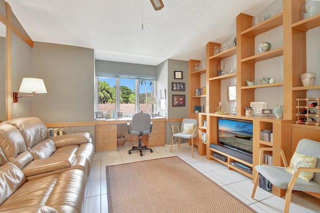 tiled office space with a textured ceiling, built in desk, and ceiling fan