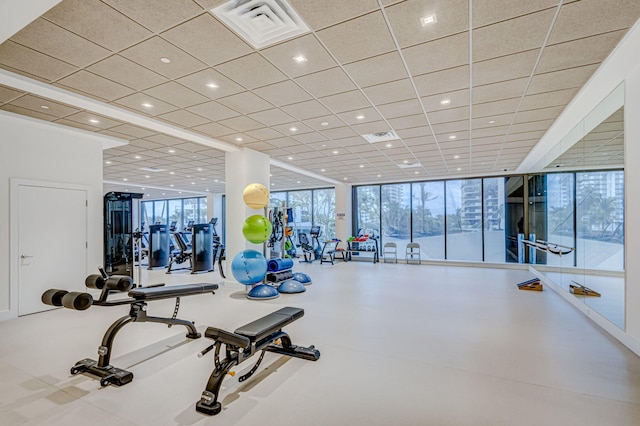 exercise room featuring expansive windows and a drop ceiling