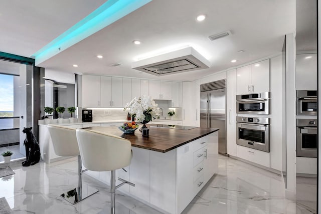 kitchen featuring a kitchen island, appliances with stainless steel finishes, a breakfast bar area, and white cabinets