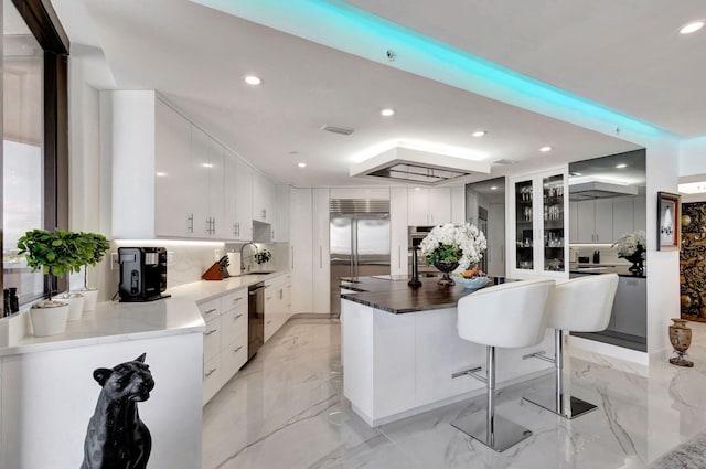 kitchen with stainless steel appliances, sink, a breakfast bar, white cabinets, and a center island