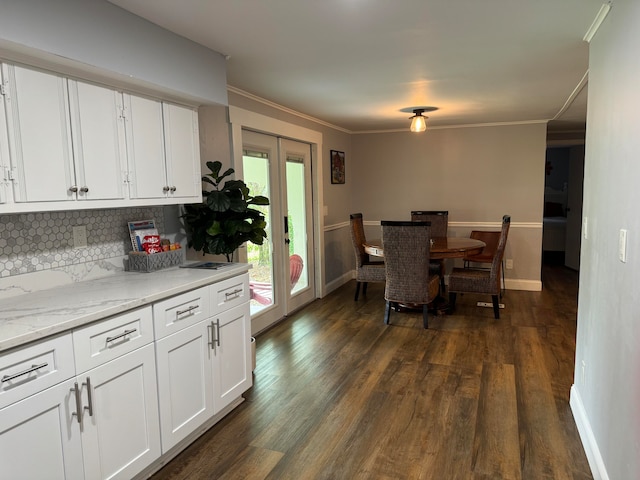 kitchen with dark wood-type flooring, white cabinetry, backsplash, and ornamental molding