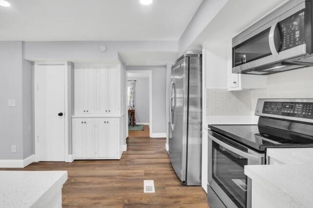 kitchen with stainless steel appliances, white cabinets, and dark hardwood / wood-style flooring