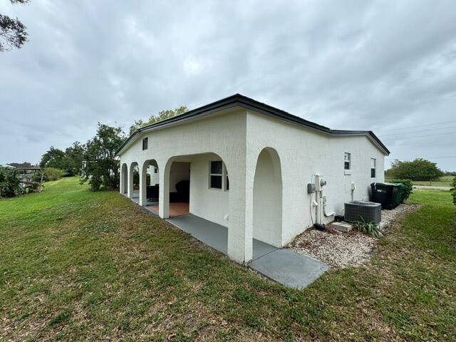 back of property featuring cooling unit, a lawn, and a patio area