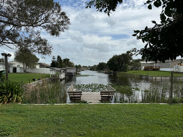 view of dock with a water view and a lawn