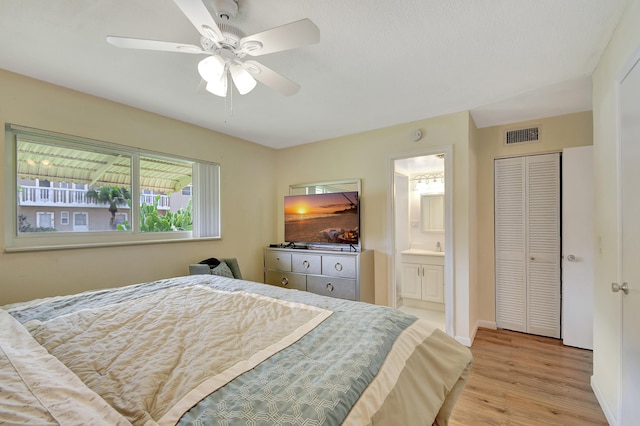 bedroom with light hardwood / wood-style floors, ceiling fan, connected bathroom, and a closet