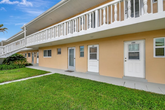 view of exterior entry featuring a yard and a balcony