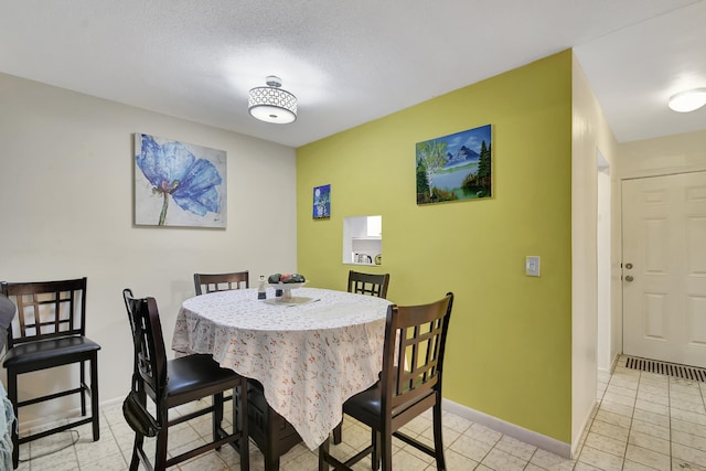 tiled dining space featuring a textured ceiling