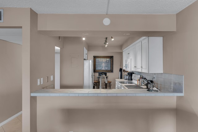 9 Royal Palm Way Unit 4020, Boca Raton, FL 33432 - kitchen featuring white appliances, tile countertops, backsplash, light tile patterned floors, and a textured ceiling