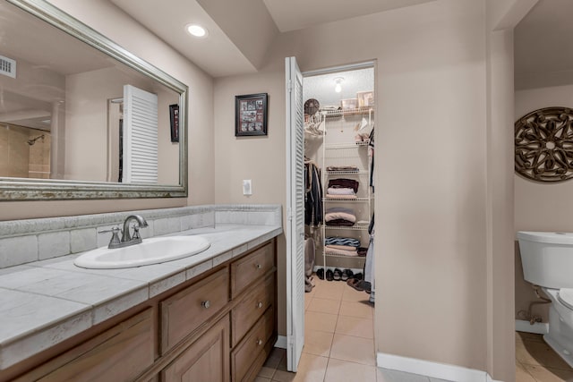 bathroom with toilet, vanity, and tile patterned floors