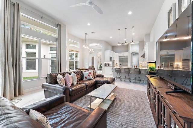 tiled living room with ceiling fan with notable chandelier