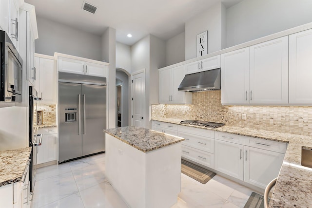 kitchen with white cabinets, stainless steel appliances, and light stone counters