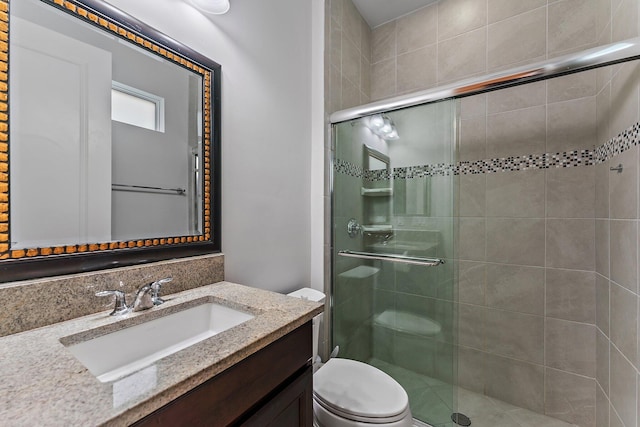 bathroom featuring vanity, toilet, and a shower with door